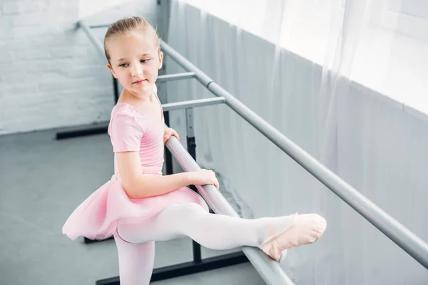 Adorable kid in pink tutu stretching and practicing in ballet school — Stock Photo