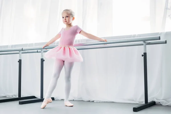 Очаровательная маленькая балерина в розовой пачке, практикующая в балетной студии — стоковое фото