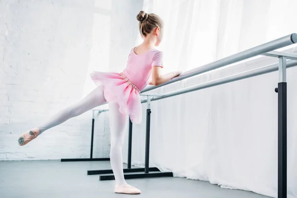 Милая маленькая балерина в розовой пачке практикующая в балетной студии — стоковое фото
