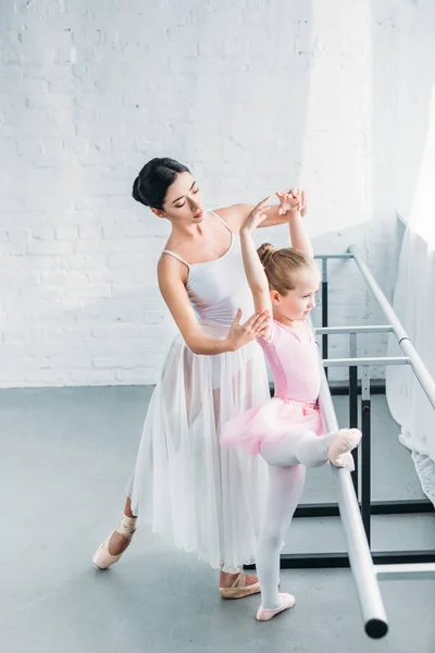Высокий угол обзора молодой учитель балета, занимающийся с очаровательным ребенком в балетной студии — стоковое фото