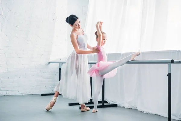 Joven profesor de ballet haciendo ejercicio con un lindo estudiante en el estudio de ballet - foto de stock