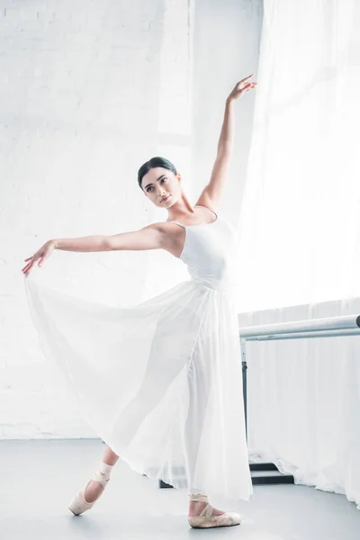 Елегантна молода балерина в білій сукні танцює в балетній студії — стокове фото