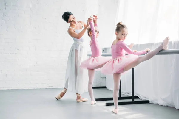 Beautiful young ballet teacher exercising with kids in ballet school — Stock Photo