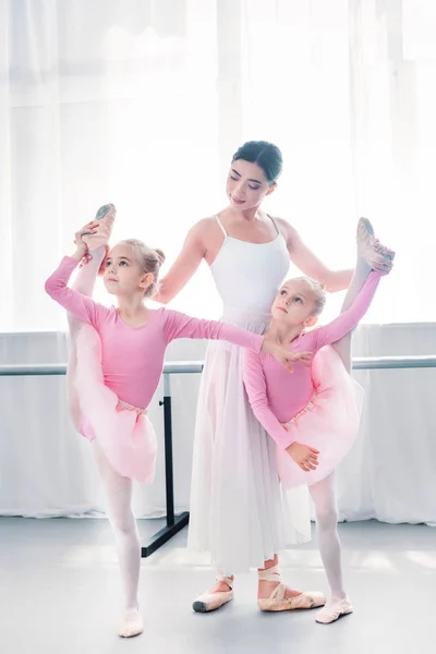 Young ballet teacher exercising with small ballerinas in ballet school — Stock Photo