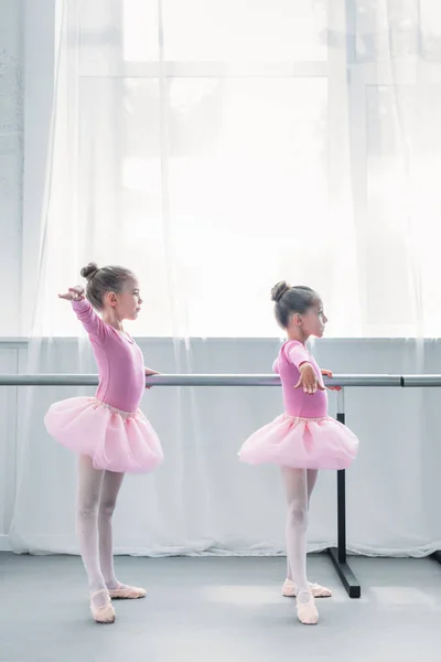Vista lateral de pequeños bailarines de ballet haciendo ejercicio en la escuela de ballet - foto de stock