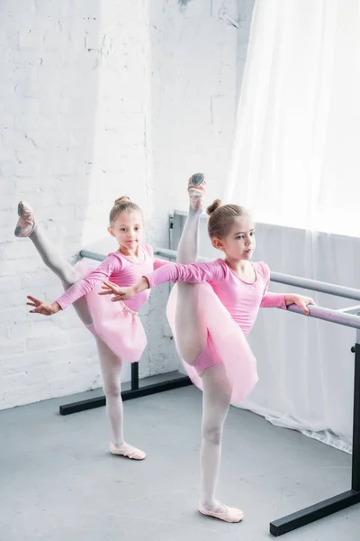 Cute little kids in pink tutu skirts stretching and dancing in ballet school — Stock Photo