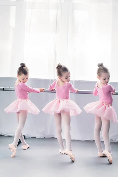 Vista trasera de pequeñas bailarinas graciosas practicando ballet en estudio - foto de stock