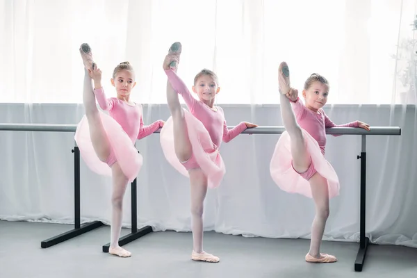 Lindos pequenos bailarinos de ballet exercitando e olhando para a câmera na escola de balé — Fotografia de Stock