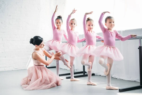 Молодая женщина обучает очаровательных детей танцам в балетной школе — стоковое фото