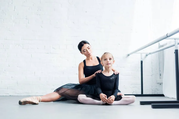 Ballet teacher and little student in black clothing exercising together in ballet school — Stock Photo