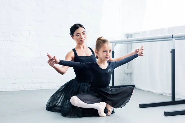 Jeune professeur de ballet formant mignon enfant flexible à l'école de ballet — Photo de stock
