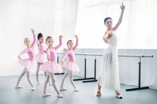 Молодий вчитель практикує балет з чарівними дітьми в рожевих спідницях — стокове фото
