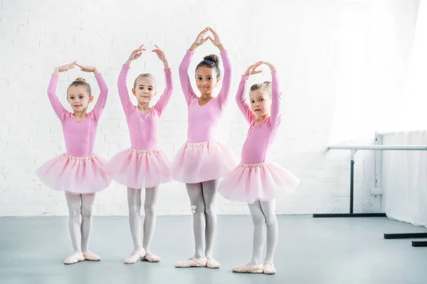 Красиві багатоетнічні діти в рожевих спідницях, що практикують балет разом — стокове фото