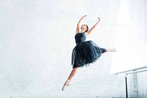 Vista de ángulo bajo de la hermosa bailarina joven bailando en el estudio de ballet - foto de stock