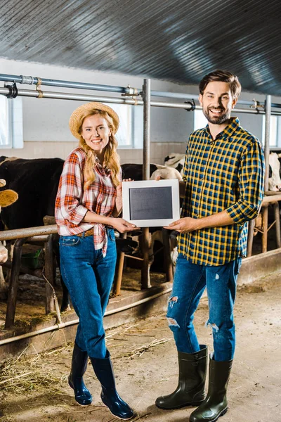 Couple d'agriculteurs souriants montrant tableau noir dans l'écurie — Photo de stock