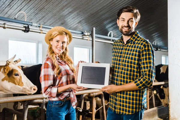 Couple of farmers showing blackboard in stable — Stock Photo