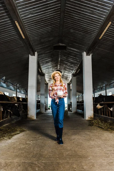 Agricultor atraente exploração jarro de leite em estábulo — Fotografia de Stock