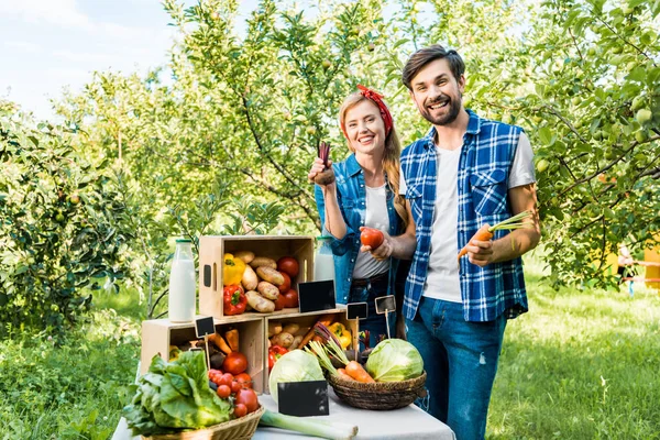 Coppia di agricoltori che mostrano ortaggi maturi al mercato agricolo — Foto stock