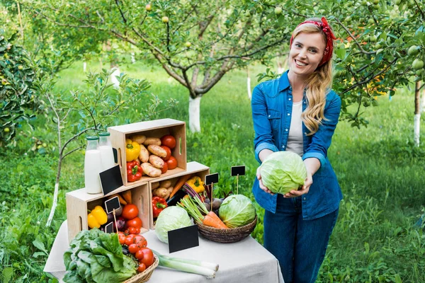 Attractive farmer showing cabbage at farmer market — Stock Photo