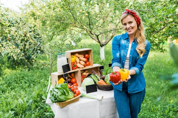 Attraktive Bäuerin zeigt reife Paprika auf Bauernmarkt — Stockfoto