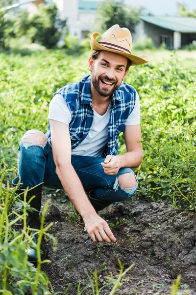 Felice bel contadino piantare semi di cardamomo in campo in azienda — Foto stock