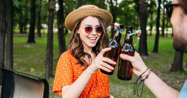 Vista parcial de casal clinking garrafas de cerveja durante bbq no parque — Fotografia de Stock