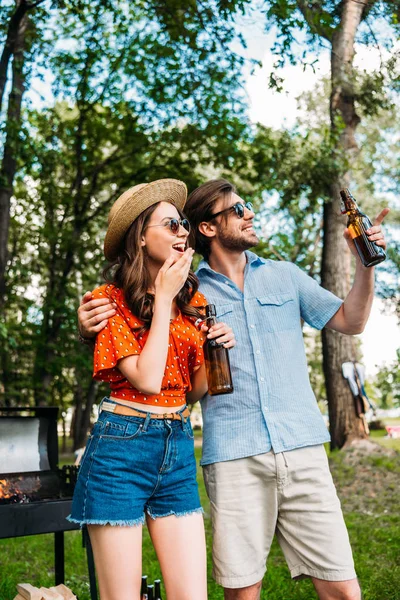 Cheerful couple in sunglasses with beer looking away in park — Stock Photo
