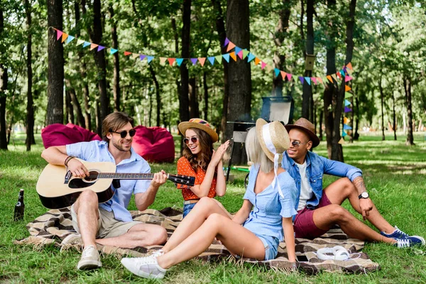 Amigos multiculturais com guitarra descansando em cobertor no parque de verão — Fotografia de Stock