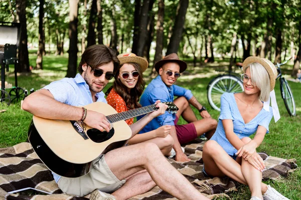 Allegri amici multiculturali con birra e chitarra a riposo nel parco estivo — Foto stock