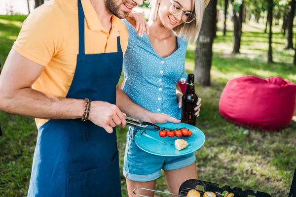 Vista parcial de pareja alegre teniendo barbacoa en el parque de verano - foto de stock