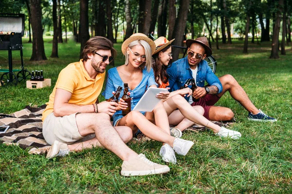 Amici interrazziali con birra e tavolo a riposo nel parco estivo — Foto stock