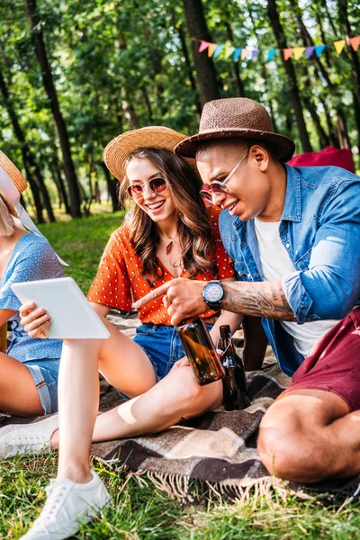 Selektiver Fokus eines fröhlichen gemischtrassigen Paares, das Tablette benutzt, während es sich mit einem Freund ausruht — Stockfoto