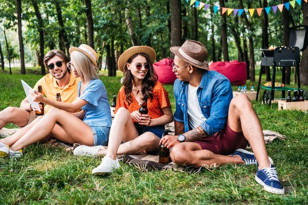 Amigos inter-raciais com cerveja e mesa descansando no parque de verão — Fotografia de Stock