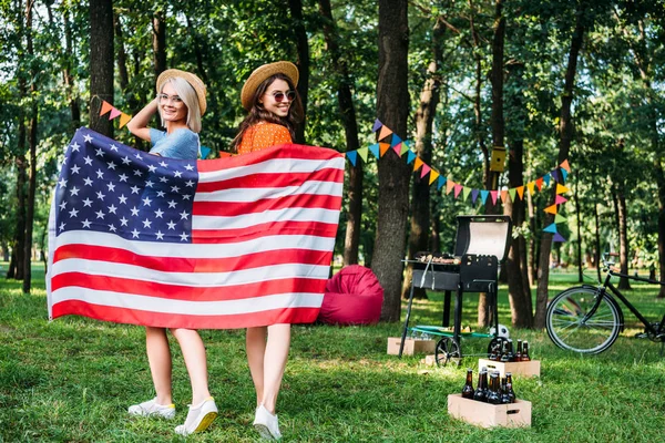 Щасливі жінки в капелюхах з американським прапором в парку — стокове фото