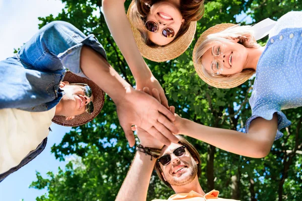 Bottom view of multiethnic smiling friends holding hands together — Stock Photo