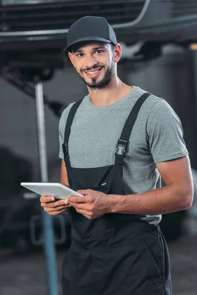 Professional auto mechanic in overalls using digital tablet — Stock Photo