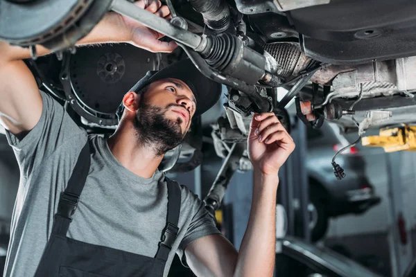 Mechanic in overalls repairing car in auto repair shop — Stock Photo