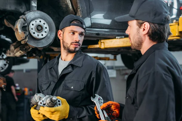 Mécanicien automobile travaillant avec la voiture et les outils en atelier — Photo de stock