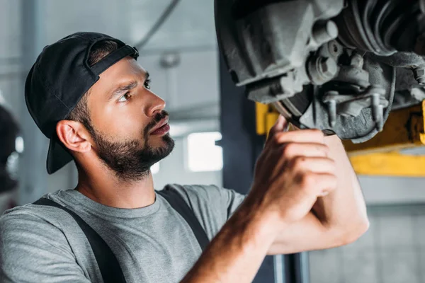 Professional auto mechanic repairing car in repair shop — Stock Photo