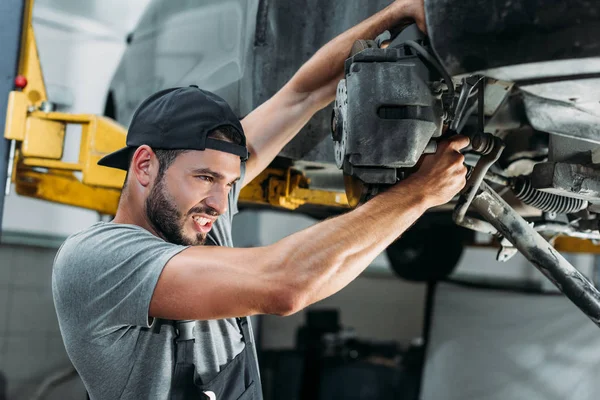 Engineer in overalls repairing car in mechanic shop — Stock Photo