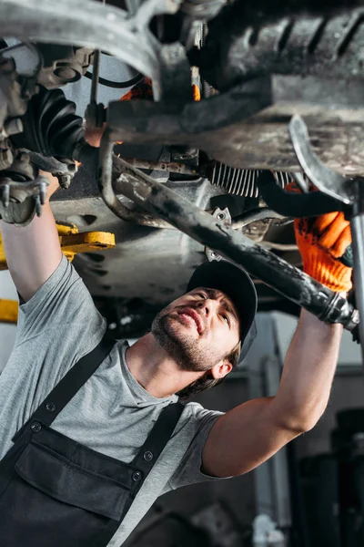 Obrero profesional en uniforme reparando coche en taller mecánico — Stock Photo