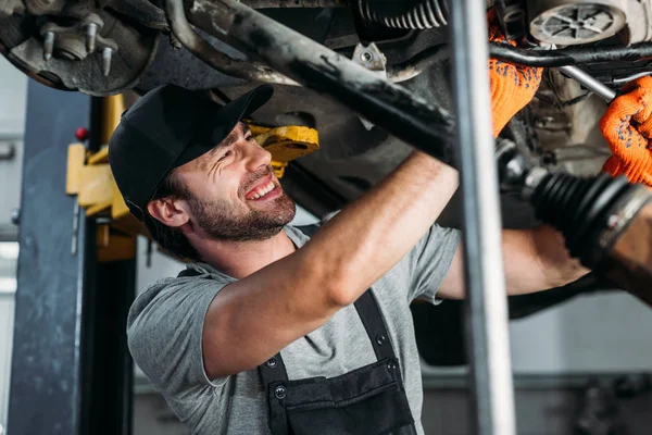 Mechaniker in Uniform repariert Auto in Werkstatt — Stockfoto