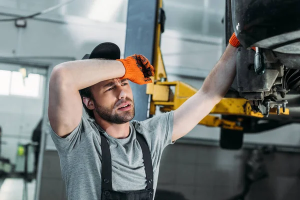 Meccanico esausto in uniforme riparazione auto in officina — Foto stock