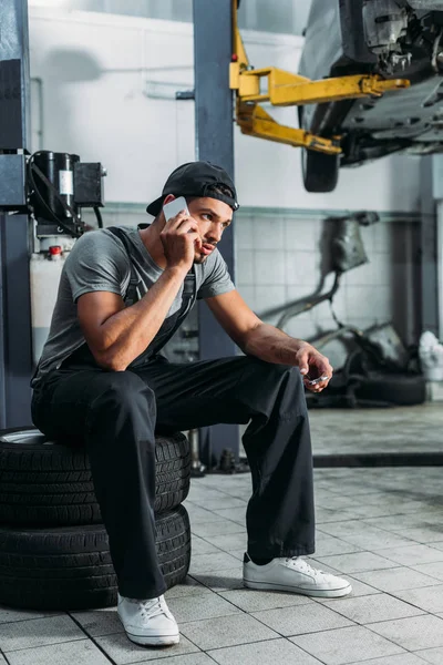 Ouvrier parlant sur smartphone et tenant clé dans un atelier de mécanique — Photo de stock