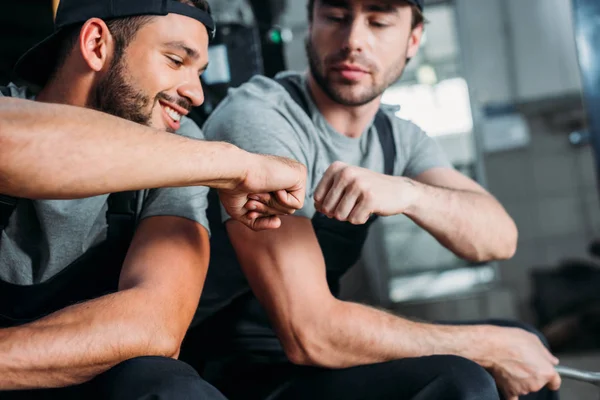 Auto mechanics bumping fists together in auto repair shop — Stock Photo
