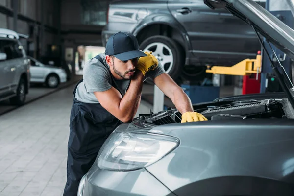 Workman in uniform repairing car in mechanic shop — Stock Photo