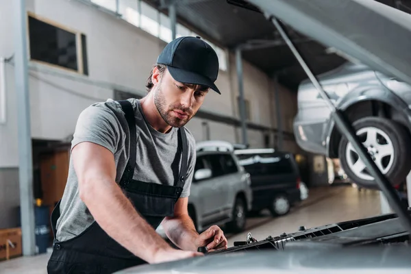 Manual worker in overalls repairing car in mechanic shop — Stock Photo