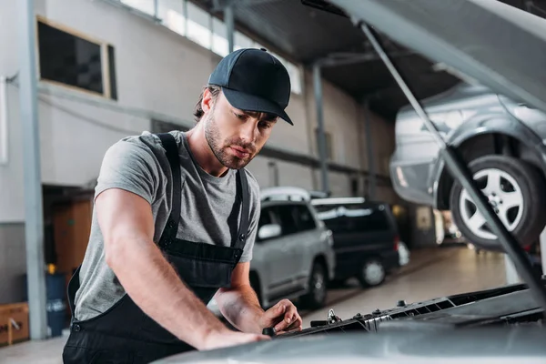 Trabajador manual en overoles reparación de coches en taller mecánico - foto de stock