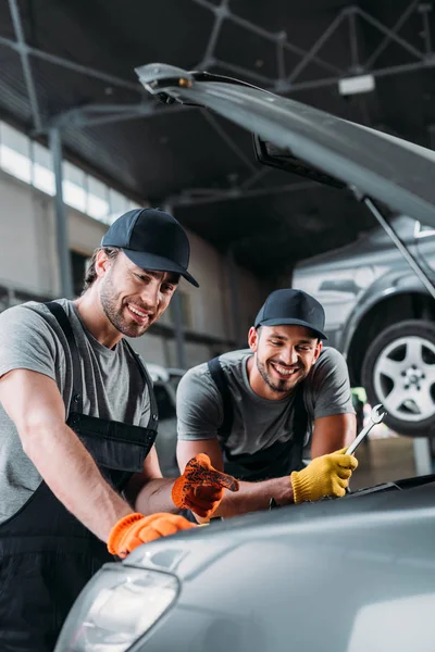 Profesional de la mecánica del automóvil sonriente reparación de coches en el taller - foto de stock