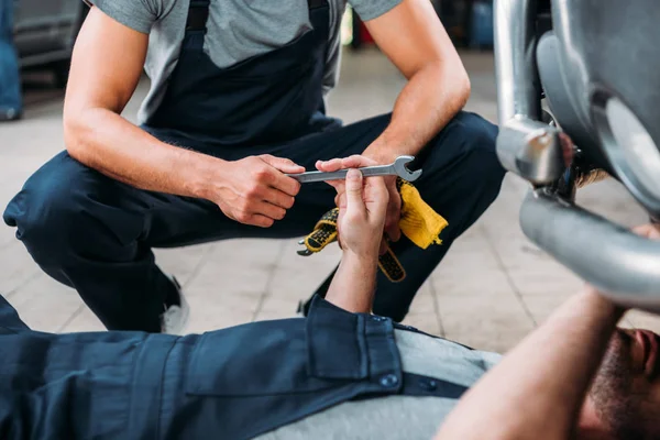 Ausgeschnittene Ansicht von Mechanikern, die in der Autowerkstatt mit Werkzeugen arbeiten — Stockfoto